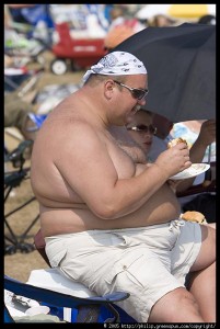 fat shirtless man eating cheeseburger